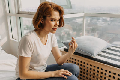 Young woman sitting on bed at home