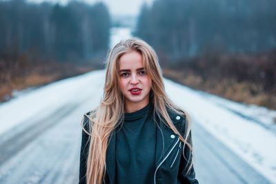 Portrait of woman standing on snow covered road