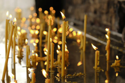 Close-up of illuminated candles in water at church