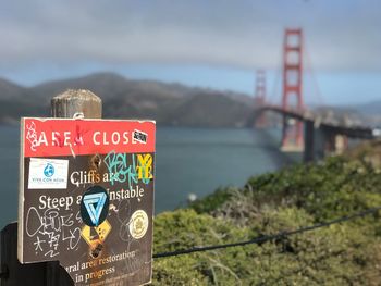 Information sign on bridge over sea against sky