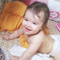 Portrait of cute shirtless baby girl lying on bed at home