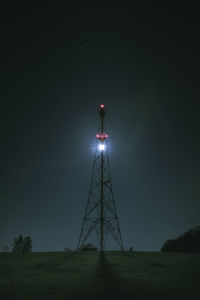 Low angle view of illuminated communications tower against sky at night