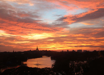 Scenic view of river against cloudy sky during sunset