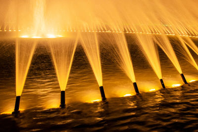 Illuminated fountain against sky at night