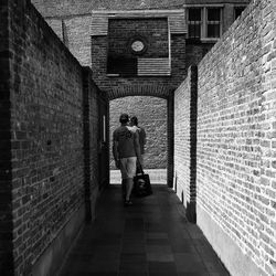 Rear view of man walking in alley amidst buildings