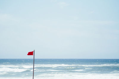 Red flag against clear sky at beach