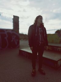 Young woman standing against sky