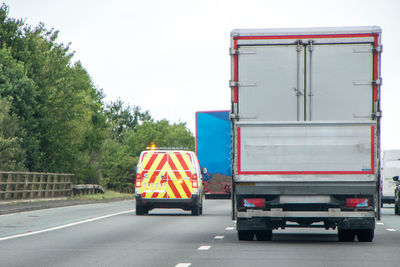 Vehicles on road against sky in city