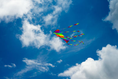 Low angle view of kites flying against blue sky