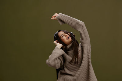 Portrait of young woman standing against wall