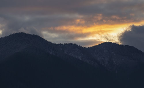 Scenic view of mountains against dramatic sky during sunset