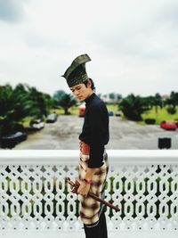 Side view of man wearing traditional clothing standing against sky