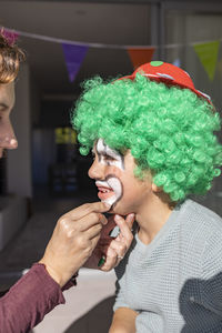 Mother painting her son's face like a clown