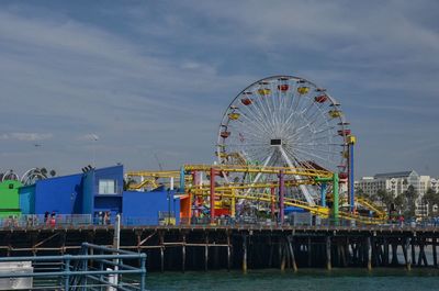 Ferris wheel by sea against sky