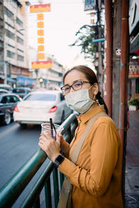 Young woman using phone while standing on street in city