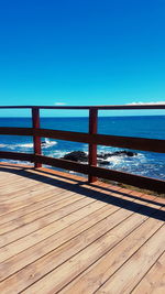 Pier over sea against clear blue sky