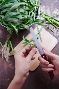 Cropped hands of woman cutting vegetables on table