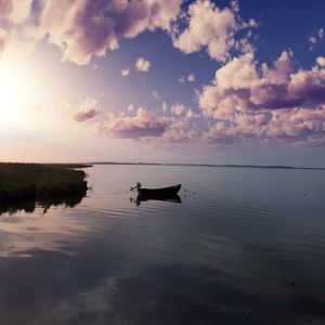 Boats in sea against cloudy sky