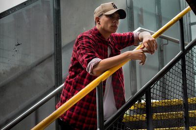 Young man looking away while standing on staircase