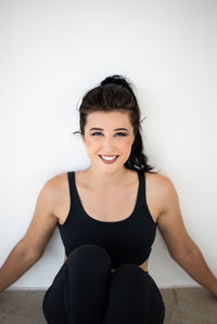 Portrait of smiling young woman against wall