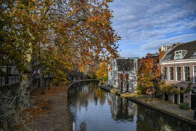 Arch bridge over canal amidst buildings against sky during autumn