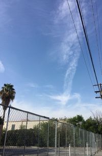 Low angle view of electricity pylon against cloudy sky