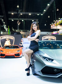 Portrait of young woman standing on car at night