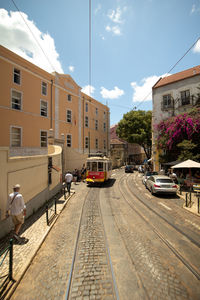 Cars on street by buildings in city against sky