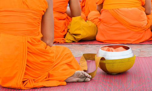 Low section of monks sitting on mat outdoors