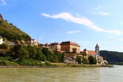 Buildings by river against sky