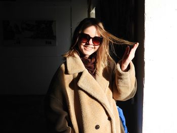 Portrait of girl wearing sunglasses standing against wall