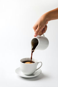 Hand pouring coffee in cup against white background