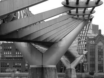 Low angle view of bridge by buildings against sky