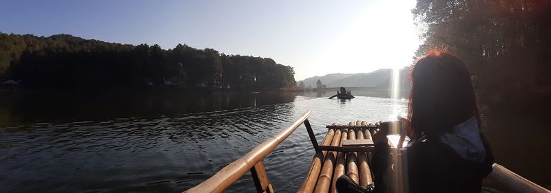 Rear view of woman on lake against sky