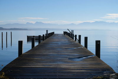 Wooden jetty on pier in sea against sky