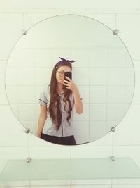 Portrait of young woman standing against wall