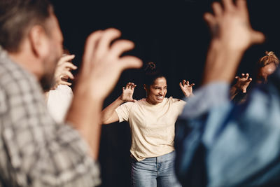 Happy actress gesturing while rehearsing with stage performers in class