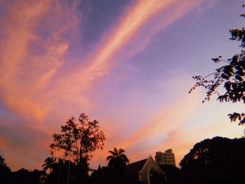 Low angle view of silhouette trees and buildings against sky during sunset