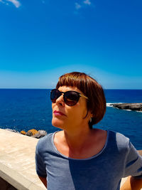 Woman wearing sunglasses against blue sea