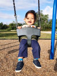 Portrait of cheerful baby boy enjoying swing at park