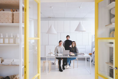 Portrait of smiling female fashion designer at desk in workshop