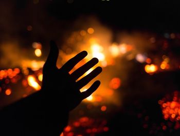 Close-up of silhouette hand against illuminated sky at sunset