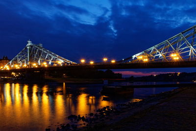 Illuminated bridge over river against sky at night