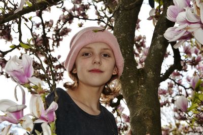 Portrait of woman with pink flowers against trees