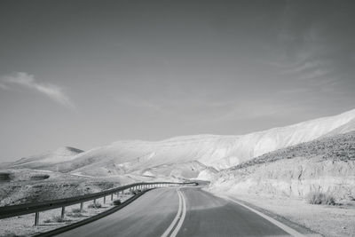 Road amidst snowcapped mountains against sky