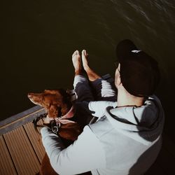 High angle view of man with dog sitting by water
