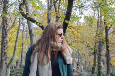 Woman standing by tree in forest