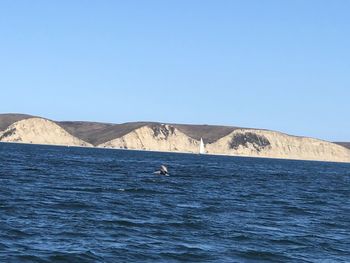 Scenic view of sea and mountains against clear sky