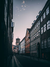 Street amidst buildings against sky during sunset