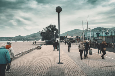 People walking on street in city against sky